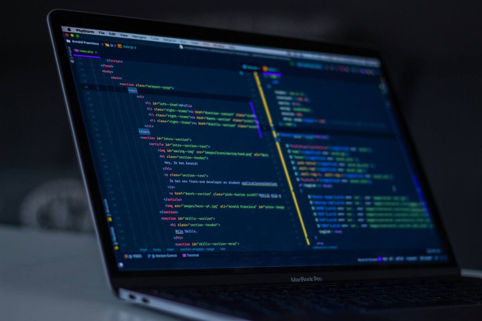 Laptop on a desk showing source code beside notebooks